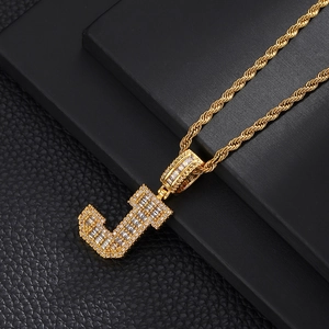 Macro view of gold J-pendant necklace with pave-set zircons and a classic rope chain