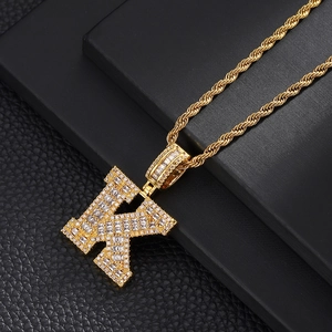 Detailed close-up of golden letter K pendant with micro-pave zircons and twist rope chain