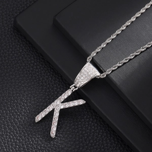 Macro-opname van een zilveren letter K hanger met zirkonia stenen en een gedraaide ketting