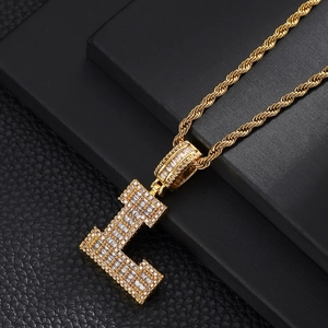Macro shot of gold letter L pendant with pavé cubic zirconia and twisted rope chain