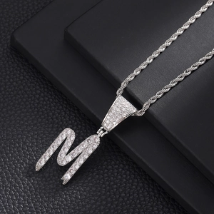 Detail van zilveren letter M hanger met zirkonia aan een gedraaide touw ketting