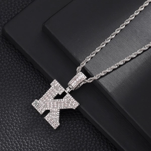 Détail macro du pendentif lettre K argenté serti de zircons cubiques et chaîne corde