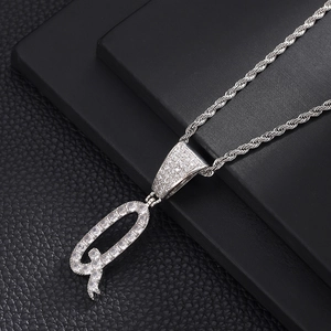 Detail van zilveren hiphop letter Q hanger met zirkonia aan een gedraaide ketting