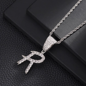 Macro-opname van de zilveren hiphop R-letter hanger met zirkonia aan een gedraaide ketting