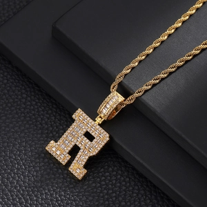 Macro detail of iced out letter R pendant with cubic zirconia and golden rope chain
