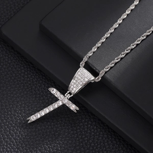 Detailopname van de hiphop-kruisvanger met micro-pave zirkonen aan een zilveren touwketting