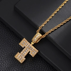 Macro detail of gold-plated letter T pendant with cubic zirconia stones on rope chain