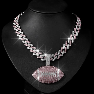 Detailed macro of iced out rugby pendant necklace on black display with sparkling pink crystals