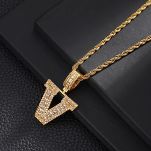 Macro detail of gold plated letter V pendant with micro paved cubic zirconia stones