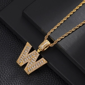 Macro view of 18K gold plated letter W pendant necklace with iced out cubic zirconia stones
