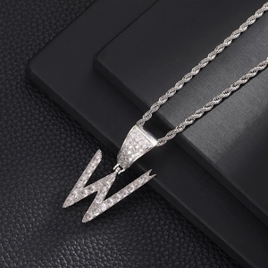 Detail van zilveren letter W hanger met zirkonia op een dikke gedraaide schakelketting