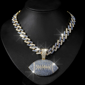 Detail of hip hop Cuban link chain with gold football pendant featuring blue and white rhinestones