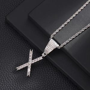 Macro-opname van zilveren hiphop letter X hanger met zirkonia aan een gedraaide touwketting