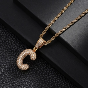 Detailed macro view of gold letter C pendant with pavé cubic zirconia on a rope chain