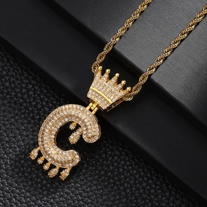 Détail macro du pendentif lettre C couronne dorée avec détails goutte et chaîne torsadée