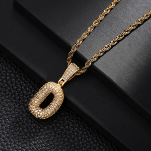 Macro detail of gold-plated letter O pendant with sparkling cubic zirconia on twist chain