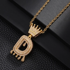 Détail d'un pendentif lettre D en or avec couronne effet gouttes et pierres de zircone
