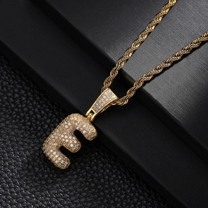 Macro shot of gold letter E pendant with cubic zirconia inlay on rope chain
