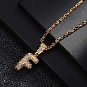 Close-up of a 18K gold letter F bubble pendant with sparkling pavé cubic zirconia