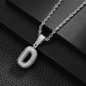 Close-up of sparkling iced out letter D pendant with silver rope chain on black stand