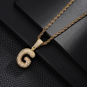 Detail of hip hop bubble letter G pendant with sparkling zircon on gold rope chain