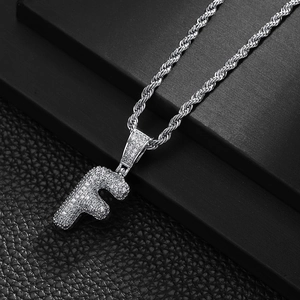Macro shot of silver bubble letter F pendant with pavé cubic zirconia on rope chain