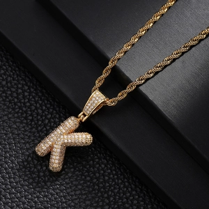 Macro detail of gold twisted rope chain with capital letter K pendant set with zircons