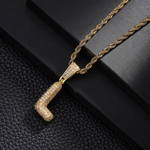 Macro shot of gold-plated hip hop letter J pendant with sparkling white cubic zirconia stones