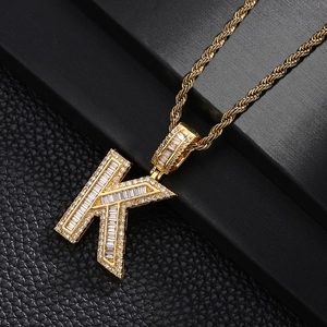 Macro detail of iced out gold plated letter K pendant necklace with cubic zirconia stones