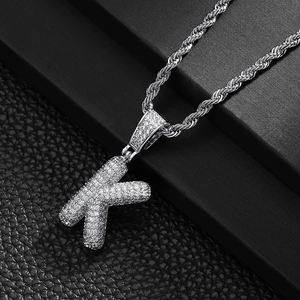 Detail view of iced out silver letter K pendant with cubic zirconia on rope chain