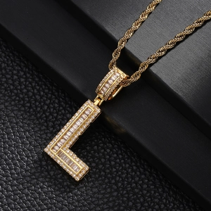 Detail of gold L-shaped pendant with cubic zirconia inlay on a black leather surface