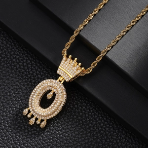 Détail macro du pendentif couronne lettre O dorée avec zircons sur fond de cuir noir