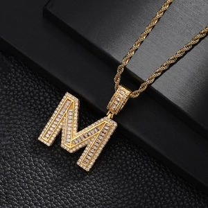 Macro shot of gold-plated letter M pendant with cubic zirconia on black leather