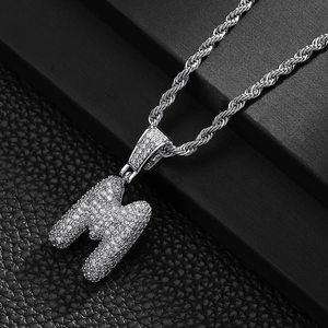 Detailed macro of silver-colored bubble letter M pendant with pave-set cubic zirconia