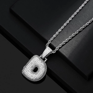 Macro detail of silver iced-out bubble letter d pendant with shiny zircon pavé and rope chain