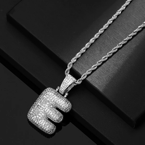 Macro view of silver bubble letter E pendant with cubic zirconia and rope chain