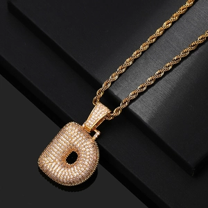 Detailed macro view of gold letter D pendant with cubic zirconia and rope chain