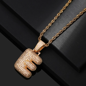 Macro view of bubble letter E pendant with cubic zirconia and gold rope chain