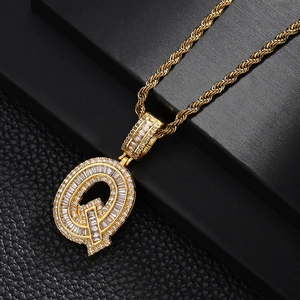 Macro detail of gold-plated letter Q pendant with cubic zirconia on rope chain