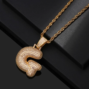 Detailed close-up of iced out gold letter G pendant with cubic zirconia on rope chain
