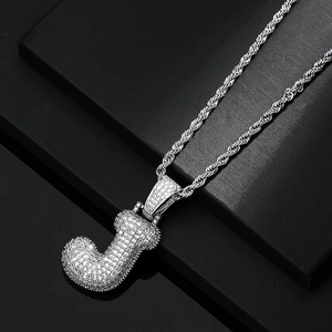 Macro view of iced out letter J pendant with white zircon stones on a silver rope chain