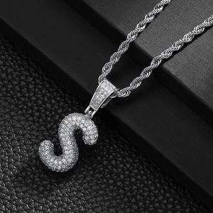 Close-up of iced out silver letter S pendant necklace with zircon and rope chain