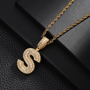 Macro shot of gold letter S pendant with baguette and round cubic zirconia stones