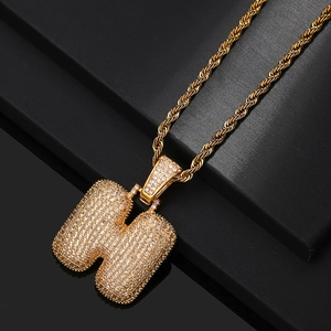 Detail of gold-plated iced out bubble letter H pendant with micro-pave zircons and rope chain