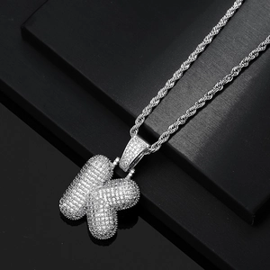 Macro detail of iced-out bubble letter K pendant with sparkling zircon stones on rope chain