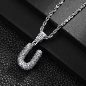 Detailed close-up of a silver letter U pendant with cubic zirconia on a rope chain