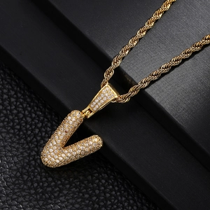 Close-up of golden letter V pendant with pavé cubic zirconia and twisted rope chain