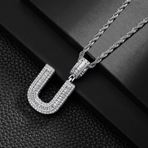 Macro shot of silver hip-hop U-letter pendant with baguette-cut sparkling zircons
