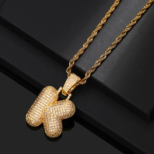 Close-up of golden bubble letter K pendant with sparkling zircons on a rope chain