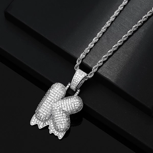 Dettaglio del ciondolo lettera K in argento stile hip hop con zirconi e effetto gocciolante